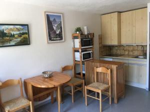 圣拉里苏朗Studio St Lary proche du centre, au calme avec vue montagne的厨房配有木桌、椅子、桌子和椅子