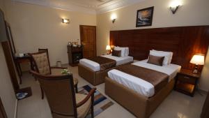 卡拉奇World Inn Karachi的酒店客房,配有两张床和椅子