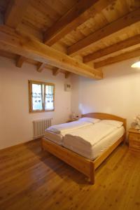 摩德纳迪-坎皮格里奥Chalet Brenta Dolomites的一间带一张床的卧室,位于带木制天花板的房间内