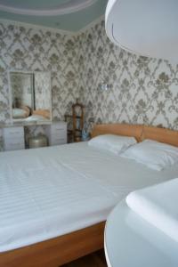 YakkasarayHiva的一间卧室配有一张带白色床单和壁纸的床