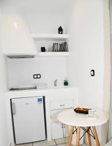 米科利维亚Galini Studios的白色的厨房配有小桌子和白色冰箱