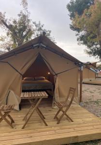 托里代巴拉KT-0094 Magnífica Tienda Tipi - Camping Miramar Playa的帐篷,甲板上配有一张床和两把椅子