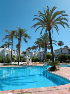 EsteponaEspectacular apartamento primera linea de playa - Golf的一座棕榈树和建筑游泳池