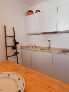 奥特朗托La Noscia - Le Dimore di Thesia的厨房配有白色橱柜和木桌