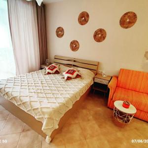 索佐波尔Студио Boho Green life Sozopol的一间卧室配有一张床和一张橙色的沙发