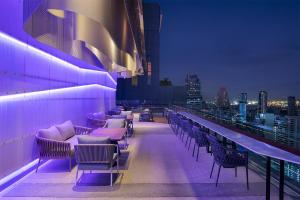 曼谷Mode Sathorn Hotel - SHA Extra Plus的大楼内屋顶酒吧,配有桌椅