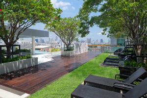 曼谷Mode Sathorn Hotel - SHA Extra Plus的一座屋顶甲板上,在建筑里种有长椅和树木