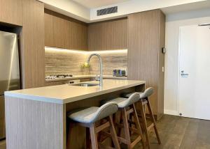黄金海岸Luxury stunning riverview 1 bedroom apt 479F的厨房配有水槽和2个吧台凳
