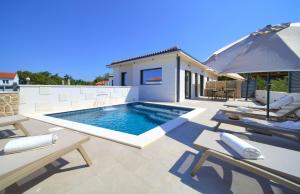 奥米沙利Villa QUARNARO with heated pool的庭院内一个带椅子和遮阳伞的游泳池