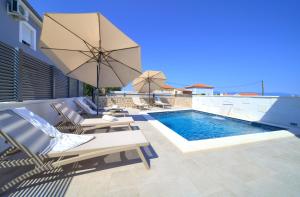 奥米沙利Villa QUARNARO with heated pool的一个带躺椅和遮阳伞的游泳池