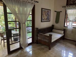 卡朗阿森Rumah Kelapa Villa Alami的一间卧室配有床和带窗帘的窗户