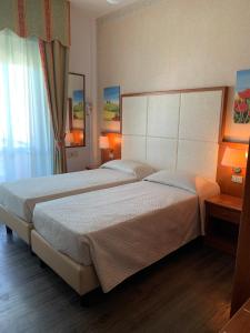 里米尼阿波罗酒店的一间卧室设有两张床、一个窗口和灯。