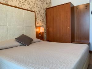里米尼阿波罗酒店的一间卧室配有一张大床和大床头板