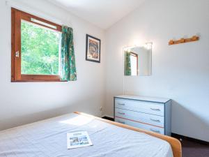 拉卡诺奥肯Holiday Home Les Landaises-9 by Interhome的一间卧室配有一张床、一个梳妆台和一扇窗户。