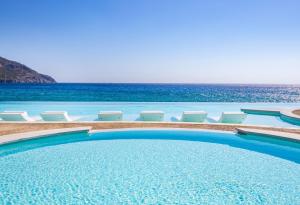 卡尔帕索斯Konstantinos Palace的一个带椅子的游泳池,背景是大海