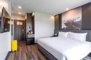 清迈Sleep Mai Thapae Chiang Mai Old City Lifestyle Hotel - SHA Plus的卧室配有白色的床和黄色的行李箱