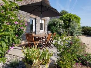 Saint-AulaireGîte de la Tuillère, maison contemporaine en bois avec vue et piscine的花园的遮阳伞下的桌椅