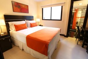 蒙得维的亚海港市场酒店的一间卧室配有一张带橙色毯子的大床