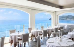 阿拉西奥斯皮亚贾格大酒店的餐厅设有白色的桌椅和大窗户。