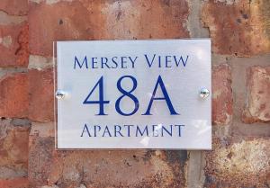 锡福斯Mersey View, Two Bedroom Apartment, Liverpool的看慈悲景公寓的砖墙上的一个标志