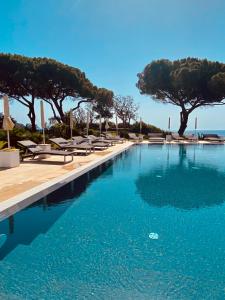阿祖罗港Resort Capo Bianco的游泳池设有躺椅和树木