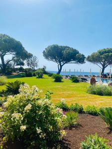 阿祖罗港Resort Capo Bianco的绿草树木和海洋的公园