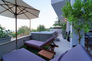 帕尔加Moonlight Suites的阳台设有长凳、热水浴池和遮阳伞。