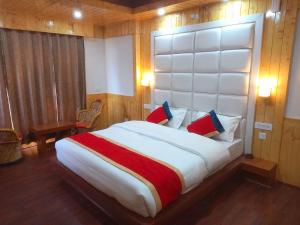 西姆拉Humble Holiday Inn Kufri Simla的一间卧室配有一张大床和大床头板