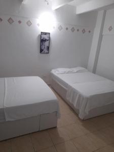 圣玛尔塔Rivera Hostel的白色墙壁客房的两张床