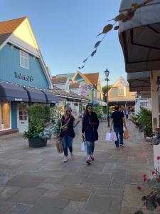 比斯特Cozy Bicester Village townhouse with garden的两个妇女走在街上,拿着购物袋