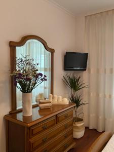 科尔库维翁Apartamento Conde的一间卧室配有带镜子的梳妆台和电视。