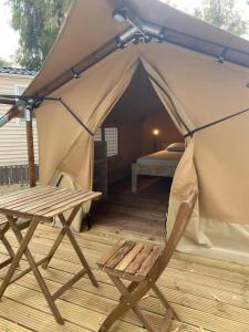 托里代巴拉KT-0094 Magnífica Tienda Tipi - Camping Miramar Playa的帐篷,配有一张床和一张椅子,位于甲板上