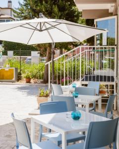 西尼加利亚德尔玛尔酒店的庭院配有白色的桌椅和遮阳伞。