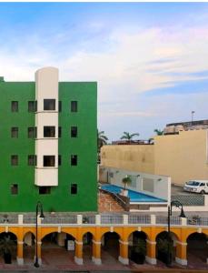 比亚埃尔莫萨Hotel Olmeca Plaza的一座绿色建筑,在停车场设有游泳池