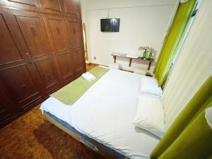 伊塔佩米林河畔卡舒埃鲁Pousada e Hospedaria Regina的卧室配有带绿色窗帘的大型白色床