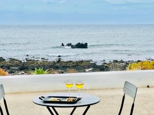 蓬塔穆赫雷斯Canaryislandshost l Lava y Mar Lanzarote的一张桌子,上面有两杯葡萄酒在沙滩上