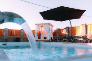 布尔奇科Cartagena Villa & Spa的一个带遮阳伞和椅子的游泳池以及一个游泳池