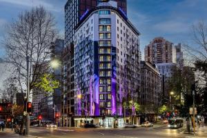 悉尼Club Wyndham Sydney, Trademark Collection by Wyndham的城市街道上一座高大的建筑,灯光紫色