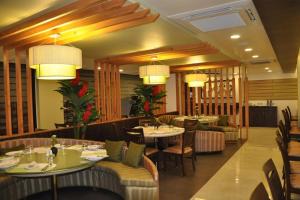 奥兰加巴德绿橄榄酒店的餐厅设有桌椅和吊灯。