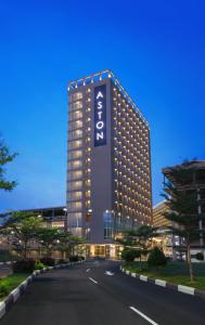 巴淡岛中心ASTON Nagoya City Hotel的一座高大的建筑,旁边有一个标志