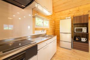 Hirakuboレジーナ石垣　ログテリアⅠ的厨房配有白色橱柜和冰箱。