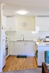 黄金海岸Sanctuary Court Unit 4的厨房铺有木地板,配有白色橱柜。