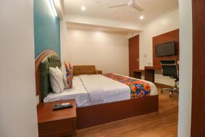 新德里FabHotel Lime Tree的一间卧室配有一张床、一张书桌和一台电视。