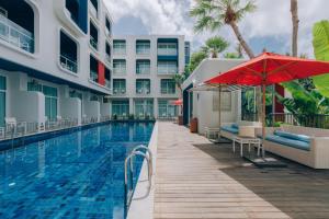 卡塔海滩Sugar Marina Hotel - NAUTICAL - Kata Beach - SHA plus的一座带红伞的酒店游泳池
