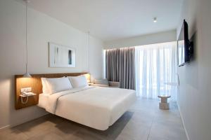 卡纳皮特萨Radisson Resort Plaza Skiathos的卧室设有一张白色大床和一扇窗户。