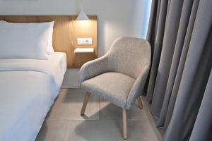 卡纳皮特萨Radisson Resort Plaza Skiathos的卧室配有床边的椅子