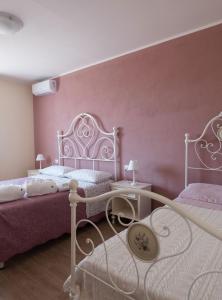 奥贝里塞Agriturismo I Grappoli的一间卧室设有两张床和粉红色的墙壁