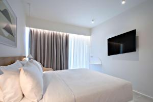 卡纳皮特萨Radisson Resort Plaza Skiathos的白色卧室配有床和平面电视