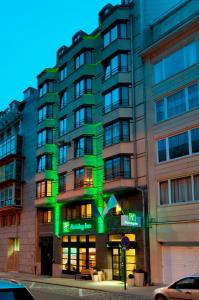 布鲁塞尔Holiday Inn Brussels Schuman, an IHG Hotel的建筑的一侧有绿灯