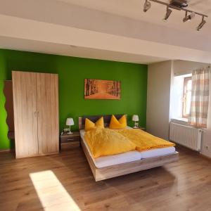 艾本施托克Wurzelrudis Hostel的一间卧室设有绿色的墙壁和一张带黄色枕头的床